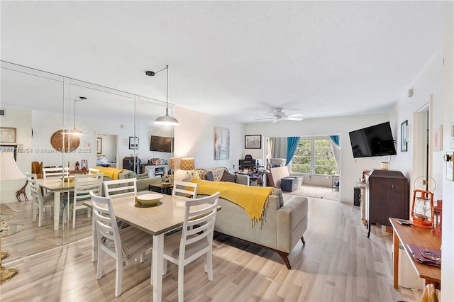 living room featuring light wood-type flooring, ceiling fan, and a textured ceiling