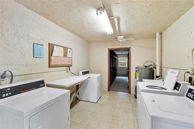 clothes washing area with ceiling fan, electric water heater, light tile patterned flooring, separate washer and dryer, and a textured ceiling