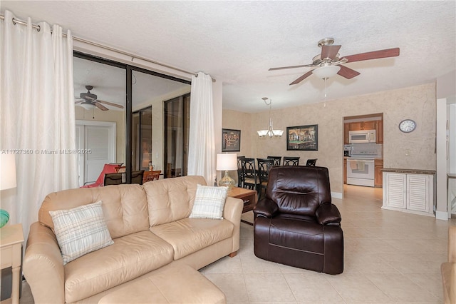 living room featuring light tile patterned floors, ceiling fan with notable chandelier, and a textured ceiling