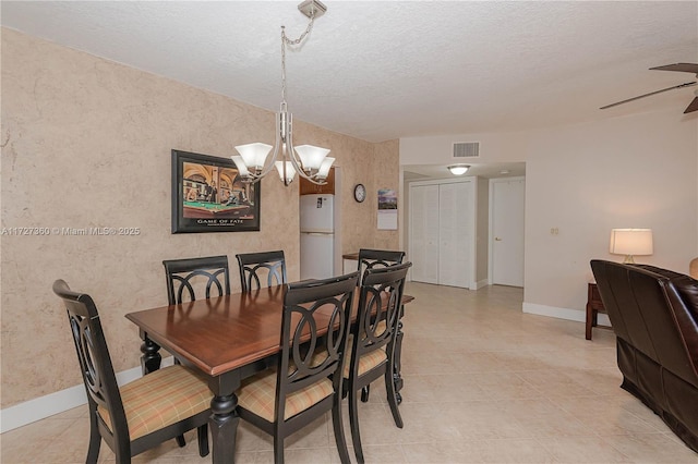 dining space featuring ceiling fan with notable chandelier and a textured ceiling