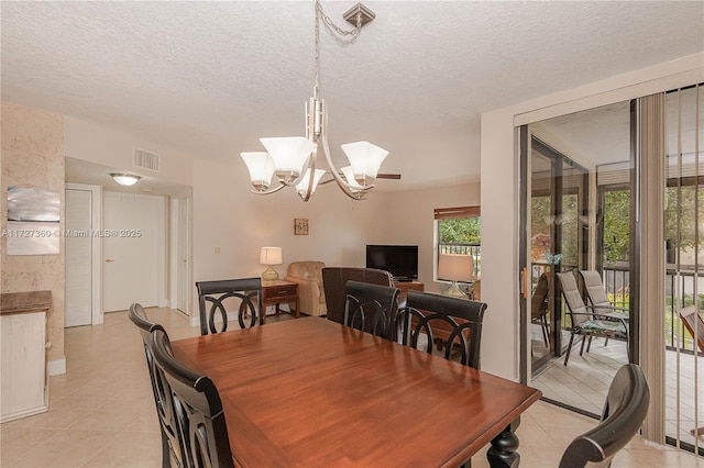 dining area featuring a textured ceiling, a notable chandelier, and light tile patterned flooring