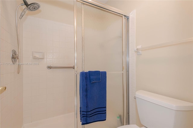 bathroom featuring toilet and a shower with door