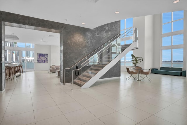 stairs with an accent wall, tile patterned floors, recessed lighting, and a towering ceiling