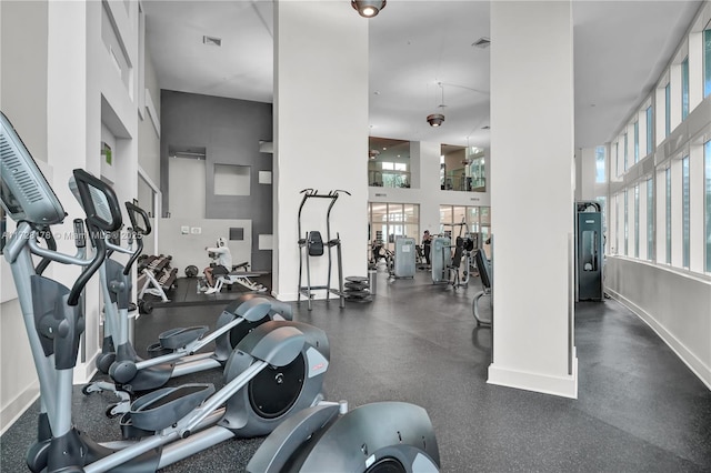 workout area with baseboards, visible vents, and a towering ceiling