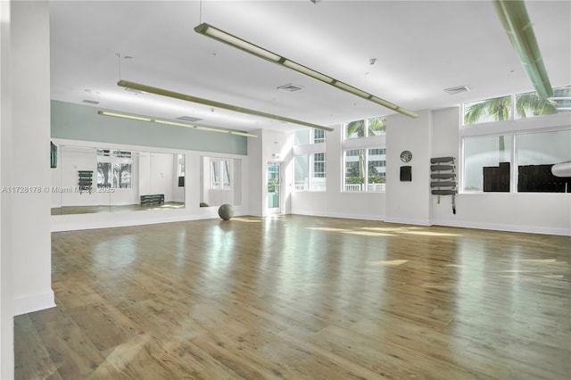 exercise room with visible vents, wood finished floors, and baseboards