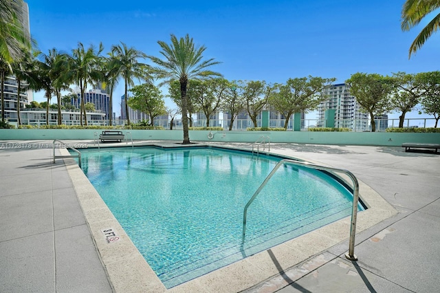 community pool with a patio and fence