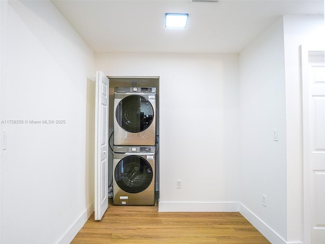 washroom with light wood-type flooring and stacked washer and clothes dryer