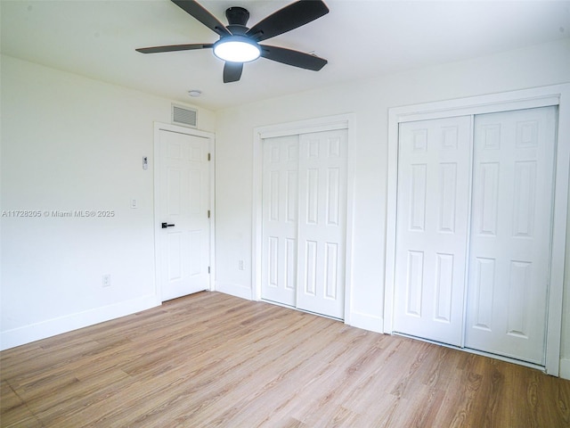 unfurnished bedroom with ceiling fan, two closets, and light hardwood / wood-style flooring