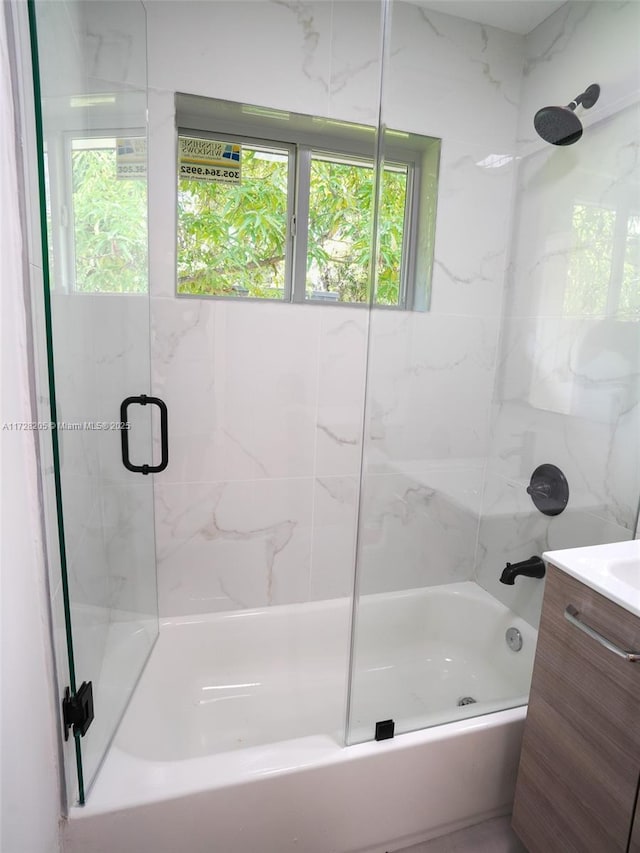 bathroom with bath / shower combo with glass door, plenty of natural light, and vanity