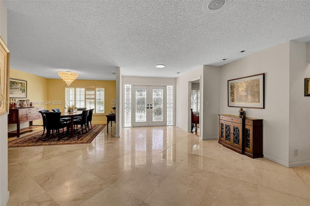 dining space with french doors, a chandelier, and a textured ceiling