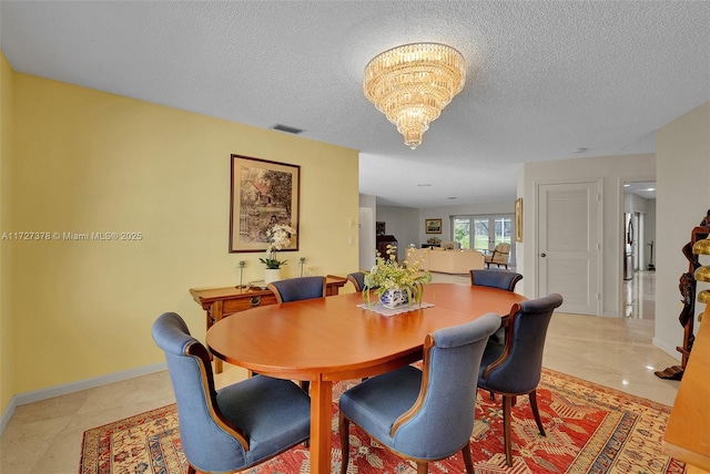 dining space with a textured ceiling and a notable chandelier