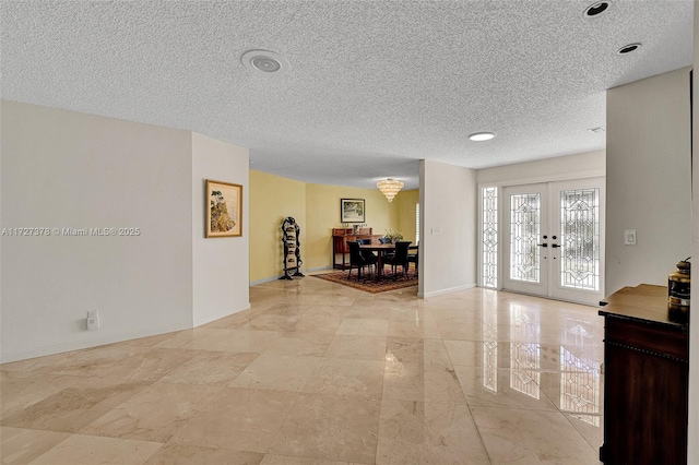 interior space with a textured ceiling and french doors