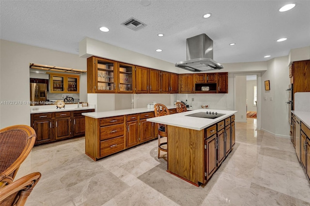 kitchen featuring a breakfast bar area, black electric stovetop, island range hood, and a center island