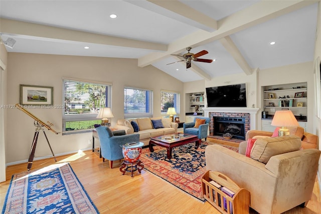 living room with ceiling fan, a fireplace, light hardwood / wood-style floors, vaulted ceiling with beams, and built in features