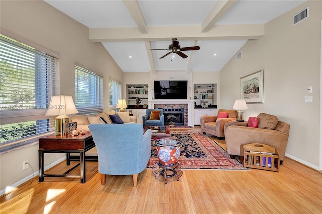 living room featuring ceiling fan, built in shelves, a fireplace, and a wealth of natural light