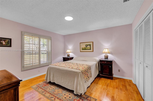 bedroom featuring a closet, a textured ceiling, and light hardwood / wood-style flooring