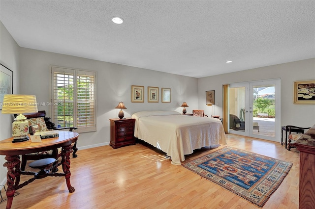 bedroom with access to exterior, a textured ceiling, french doors, and light wood-type flooring