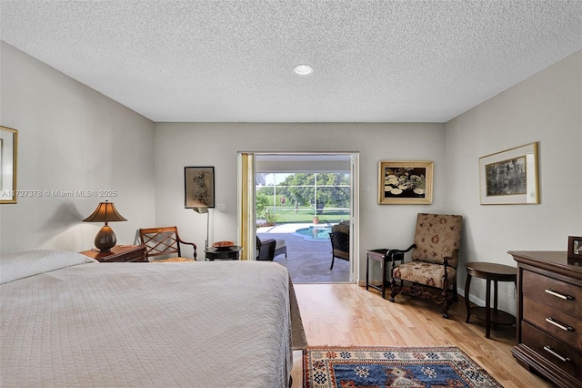 bedroom with light hardwood / wood-style floors, a textured ceiling, and access to outside