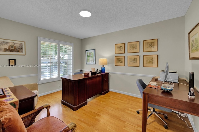 office space featuring light wood-type flooring and a textured ceiling