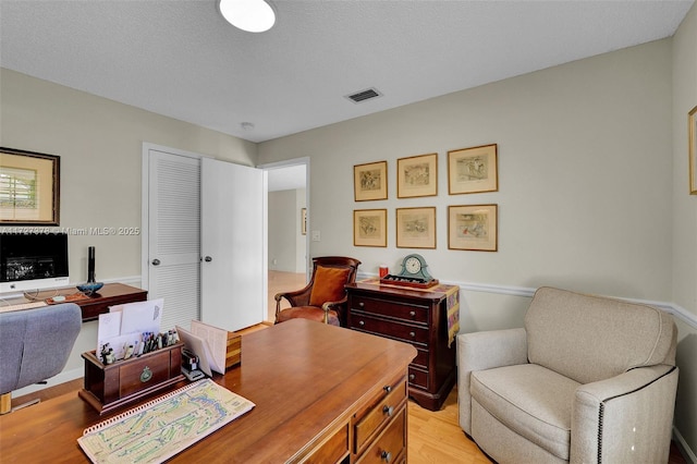 home office featuring a textured ceiling and light hardwood / wood-style floors