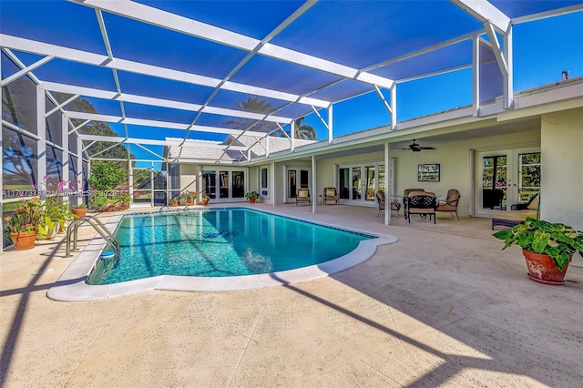 view of pool with glass enclosure, a patio area, ceiling fan, and french doors