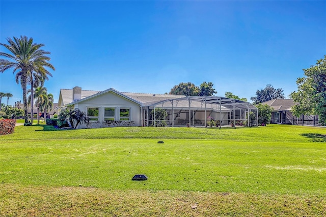 back of property with a lawn and glass enclosure