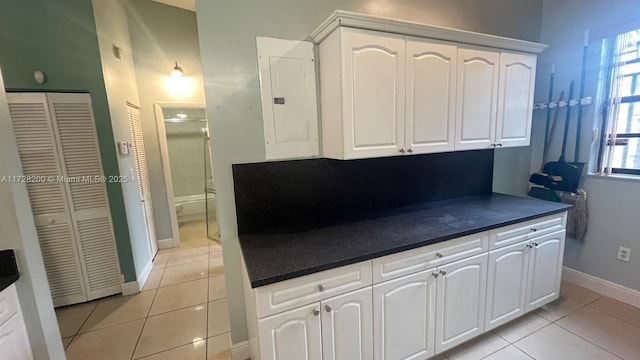 kitchen with white cabinets, light tile patterned flooring, and electric panel