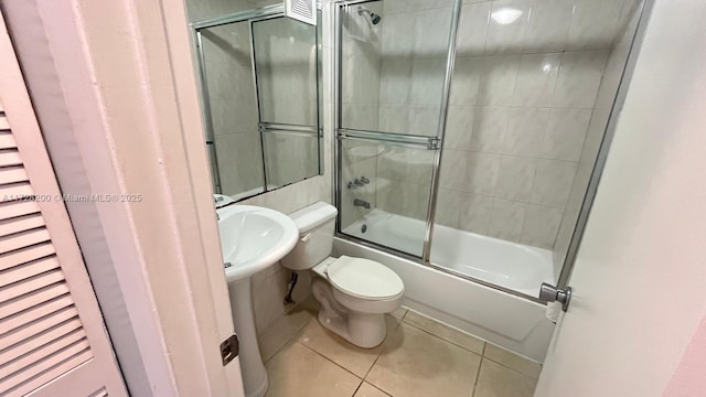 bathroom with toilet, tile patterned floors, and combined bath / shower with glass door