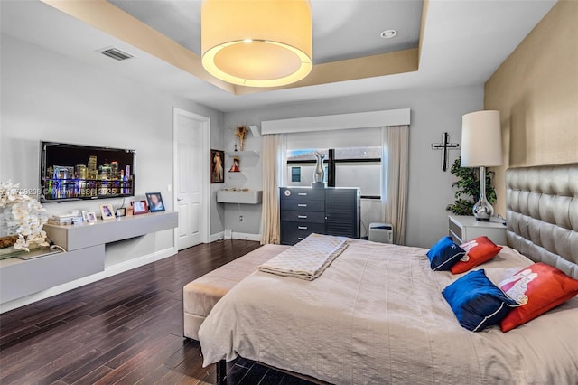 bedroom featuring dark wood-type flooring and a raised ceiling