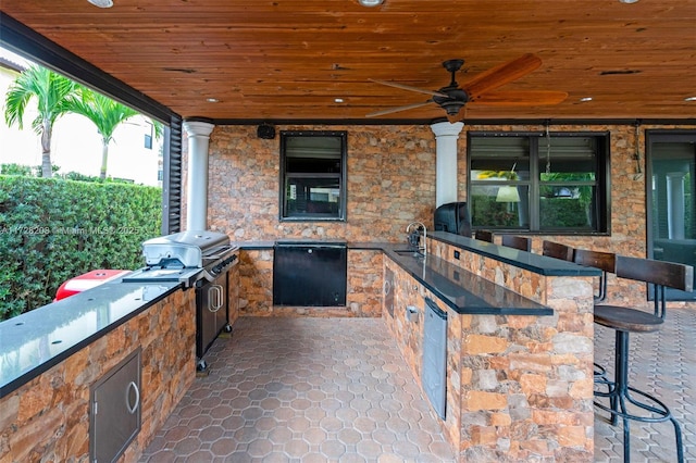 view of patio featuring ceiling fan, an outdoor kitchen, and a wet bar