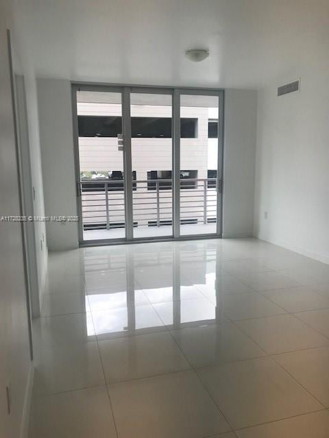 unfurnished room featuring tile patterned flooring, a healthy amount of sunlight, and expansive windows