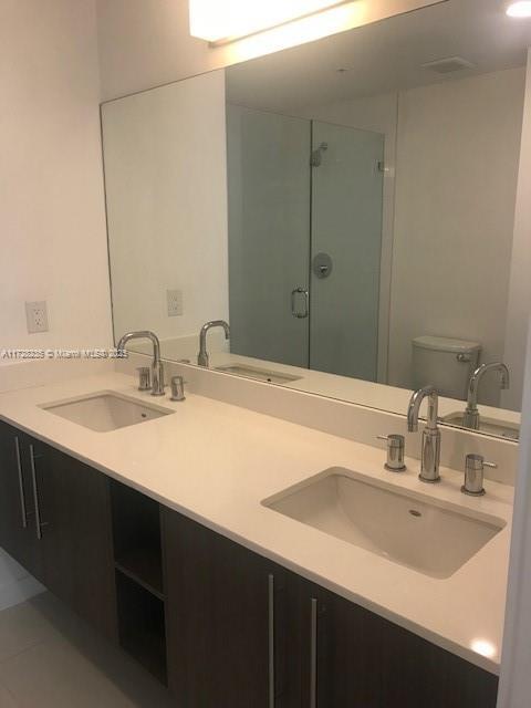 bathroom featuring toilet, walk in shower, tile patterned floors, and vanity