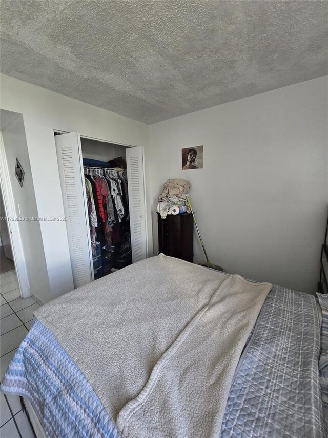 bedroom with tile patterned flooring, a closet, and a textured ceiling