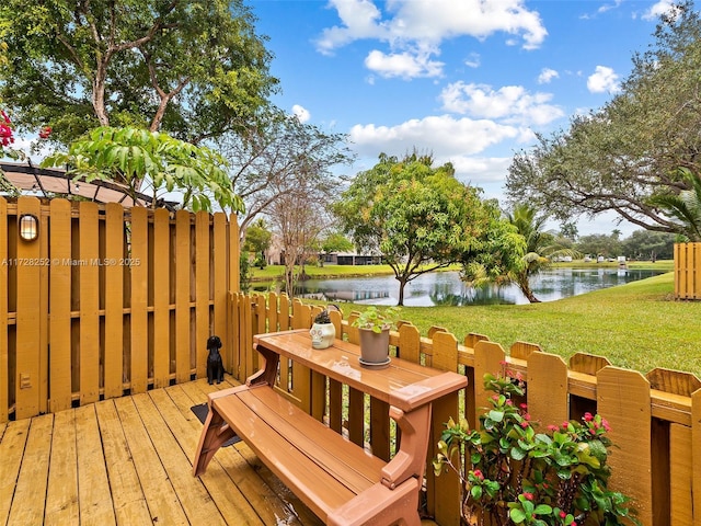 wooden terrace with a water view and a yard