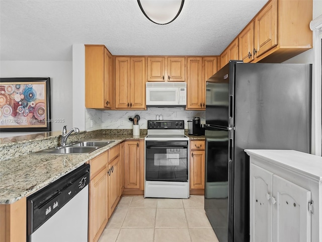 kitchen featuring dishwasher, electric range oven, sink, black refrigerator, and light tile patterned floors