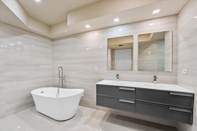 bathroom with a tub, tile walls, and vanity