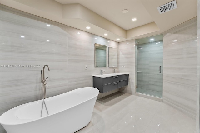 bathroom featuring tile walls, vanity, and separate shower and tub