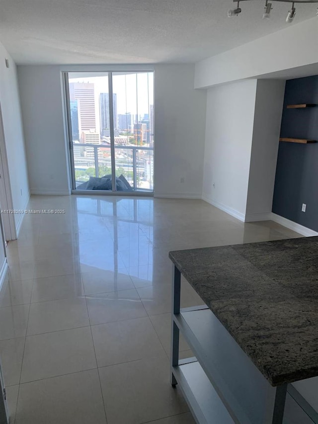 tiled empty room featuring floor to ceiling windows