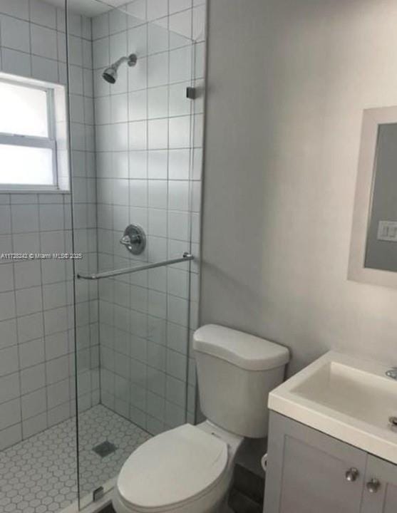 bathroom with toilet, vanity, and a shower with door