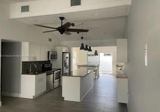 kitchen featuring a center island, white cabinetry, stainless steel appliances, decorative backsplash, and ceiling fan