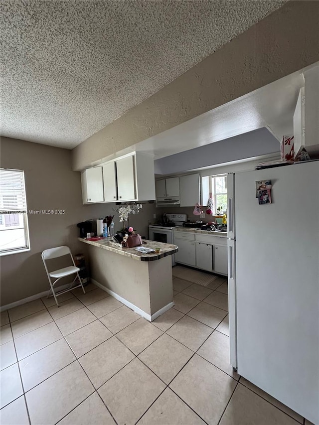 kitchen featuring kitchen peninsula, white appliances, white cabinetry, a textured ceiling, and light tile patterned floors