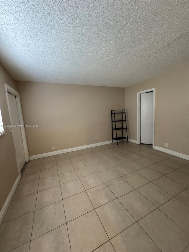 tiled empty room featuring a textured ceiling