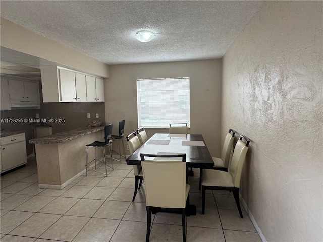 dining area with a textured ceiling and light tile patterned flooring