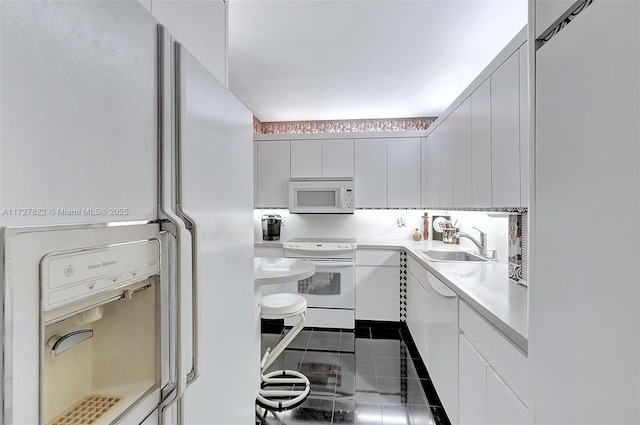 kitchen featuring white appliances, modern cabinets, light countertops, white cabinetry, and a sink