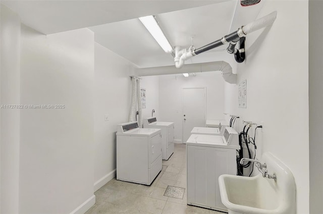 shared laundry area featuring a sink, washer and clothes dryer, and baseboards