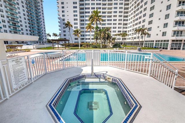 pool with a patio area and a hot tub