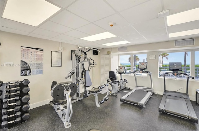 workout area featuring a paneled ceiling, visible vents, and plenty of natural light