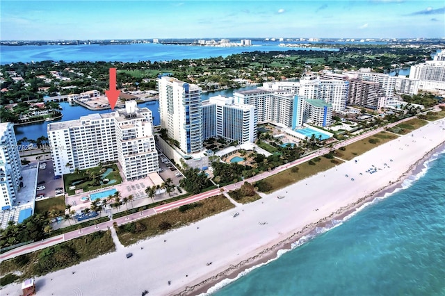 drone / aerial view featuring a water view, a city view, and a view of the beach