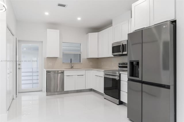 kitchen with white cabinets, backsplash, appliances with stainless steel finishes, and sink