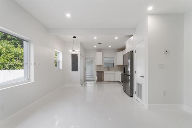 kitchen featuring light tile patterned floors, white cabinetry, appliances with stainless steel finishes, decorative light fixtures, and sink